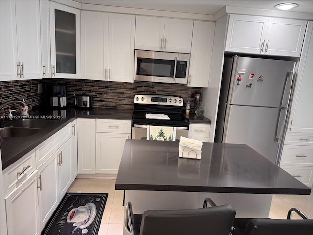 kitchen with white cabinetry, sink, backsplash, and stainless steel appliances