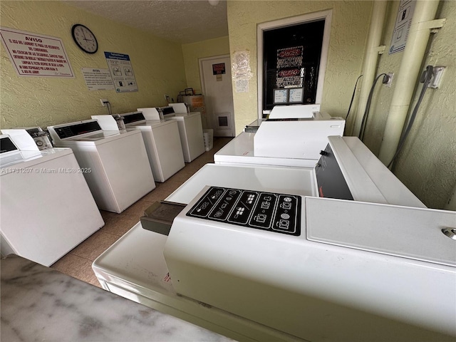 clothes washing area featuring light tile patterned floors, a textured ceiling, and washer and clothes dryer