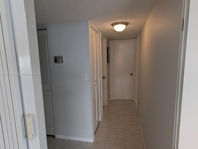 corridor with a textured ceiling and light tile patterned floors