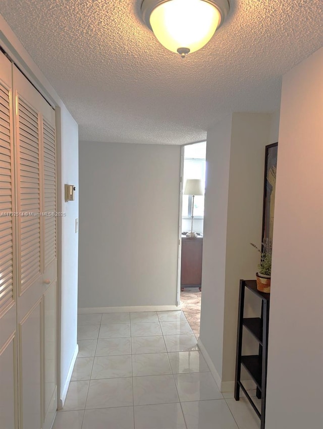 corridor with light tile patterned floors and a textured ceiling