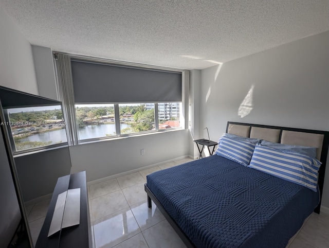 tiled bedroom with a textured ceiling and a water view