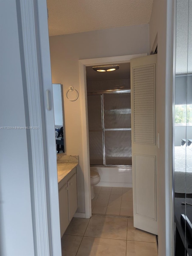 full bathroom with tile patterned flooring, vanity, enclosed tub / shower combo, and toilet