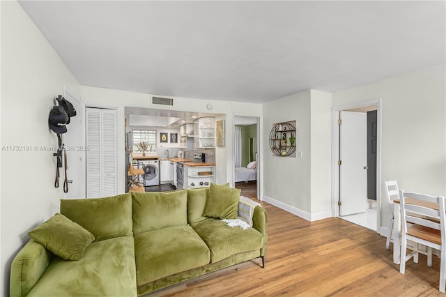 living room featuring washer / clothes dryer and light hardwood / wood-style floors