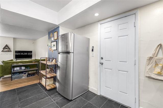 kitchen with dark tile patterned floors and stainless steel refrigerator