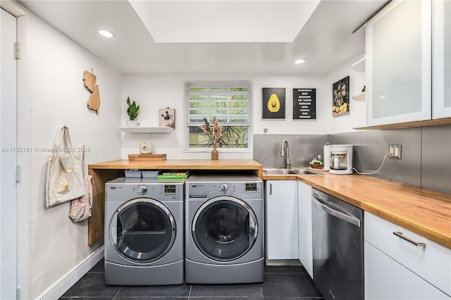 clothes washing area with sink, washer and dryer, and dark tile patterned flooring