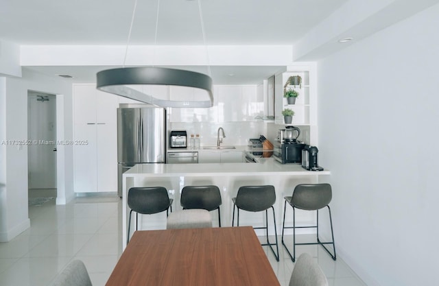 kitchen featuring white cabinetry, appliances with stainless steel finishes, a kitchen bar, and kitchen peninsula