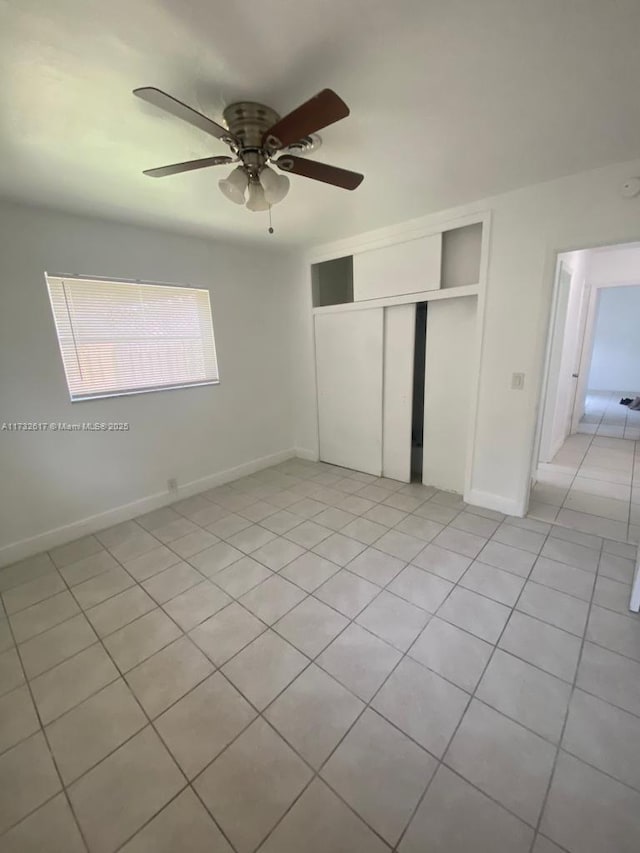 unfurnished bedroom with light tile patterned floors, ceiling fan, and a closet