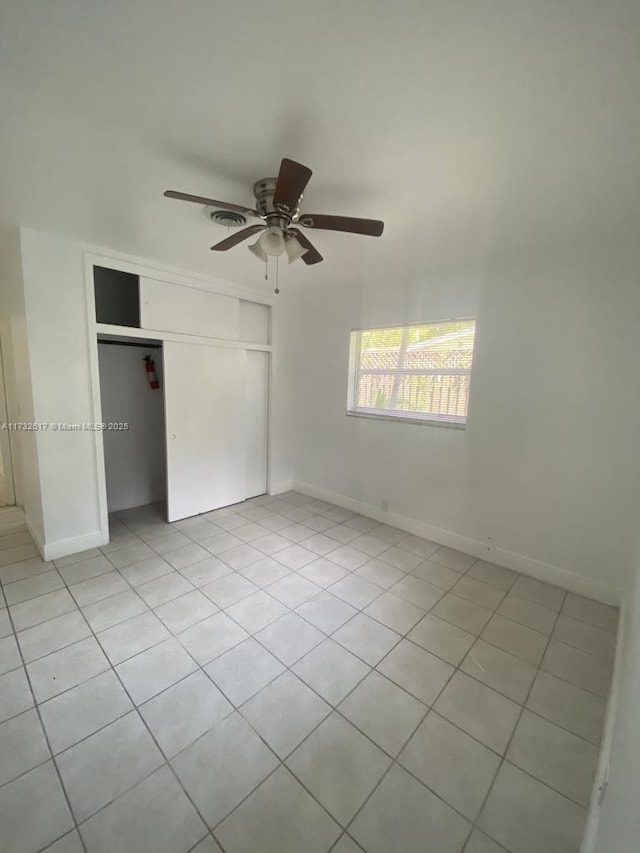 unfurnished bedroom with light tile patterned floors, ceiling fan, and a closet