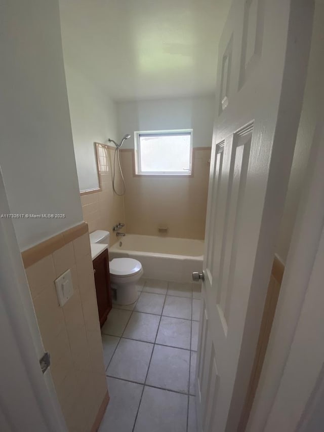 full bathroom with tile walls, vanity, tile patterned floors, toilet, and tiled shower / bath