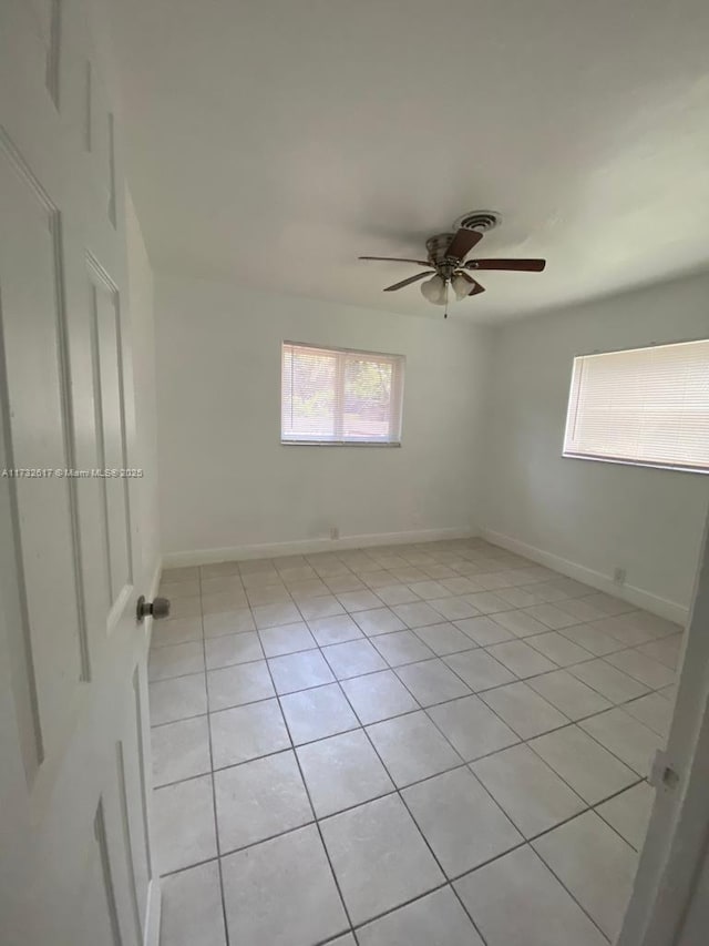 empty room with ceiling fan and light tile patterned floors