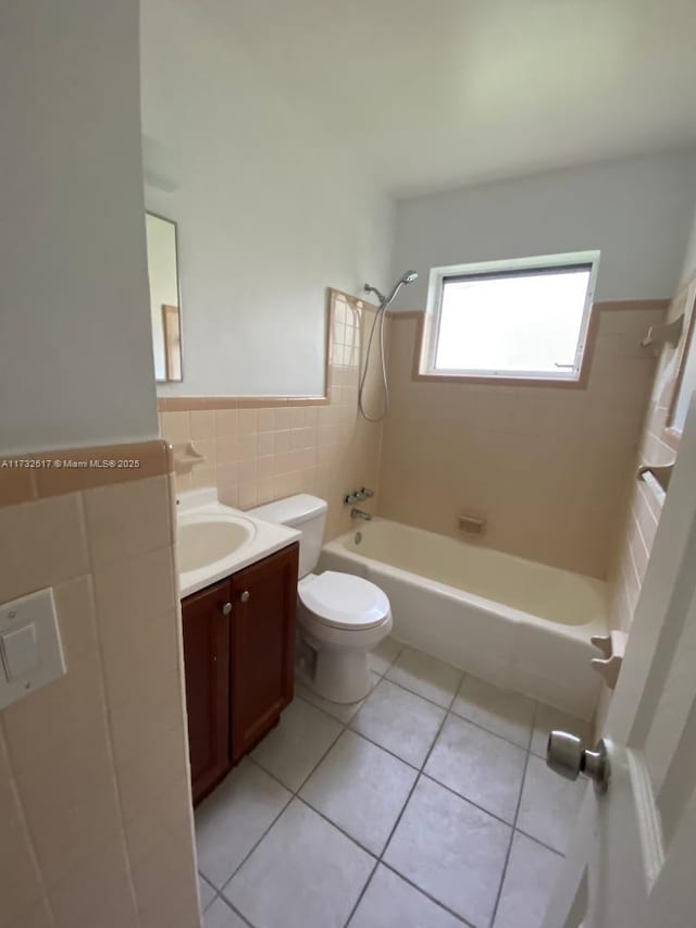 full bathroom with tile patterned floors, toilet, tiled shower / bath, tile walls, and vanity