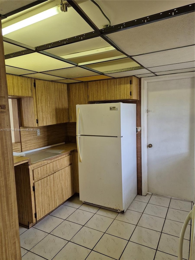 kitchen with light tile patterned floors, wood walls, and white refrigerator