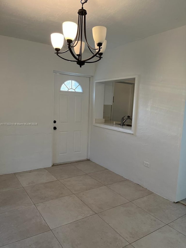 foyer with a chandelier, sink, and light tile patterned floors