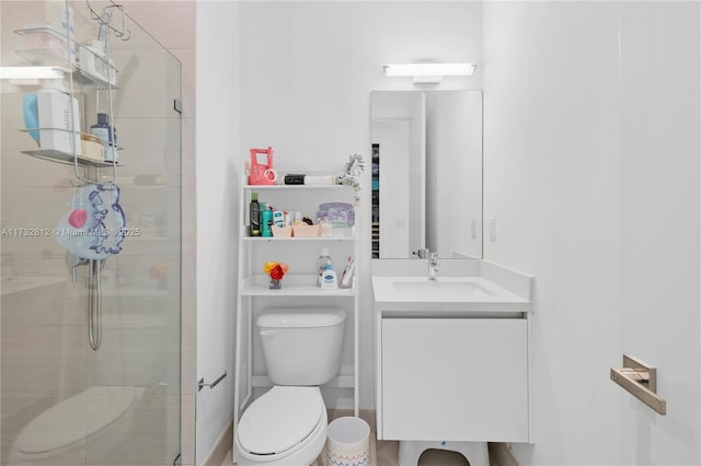 bathroom featuring a shower with door, vanity, and toilet