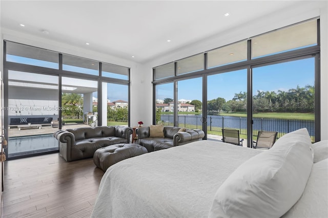 bedroom featuring multiple windows, wood-type flooring, floor to ceiling windows, and a water view