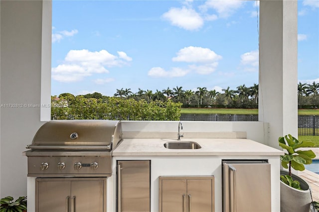 view of patio / terrace with a water view, grilling area, exterior kitchen, and sink