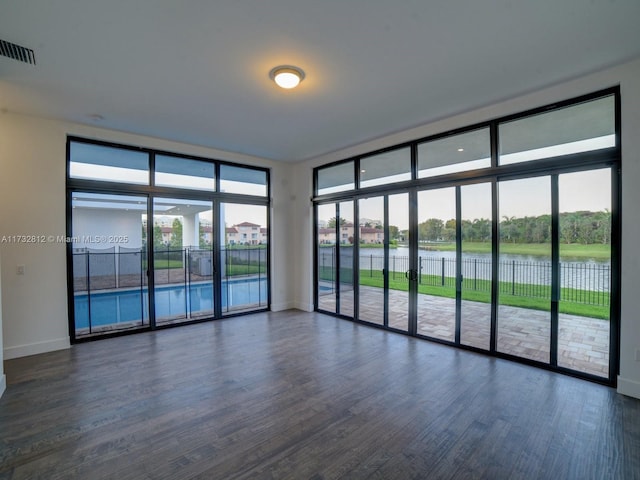 unfurnished room with a water view, expansive windows, and dark hardwood / wood-style floors