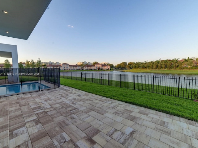 view of swimming pool featuring a patio, a water view, and a yard