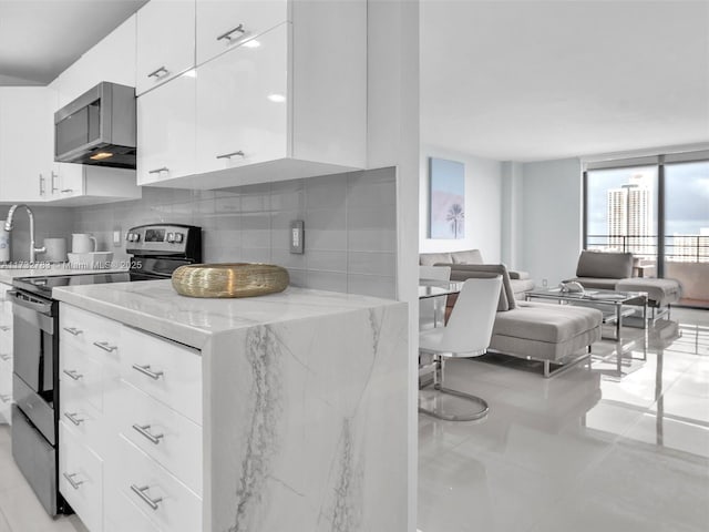 kitchen with light stone counters, light tile patterned floors, electric stove, decorative backsplash, and white cabinets