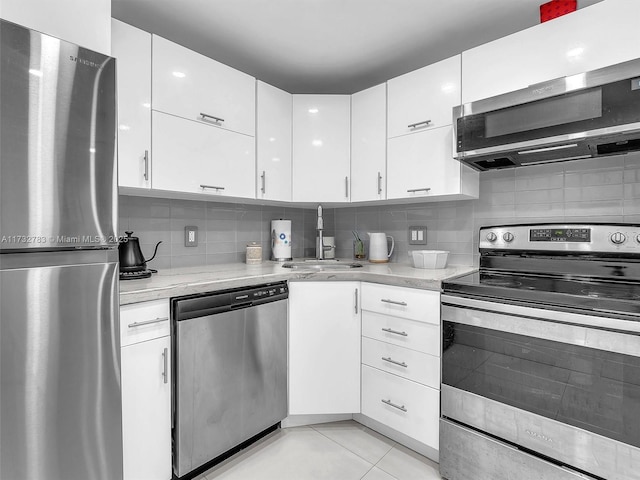 kitchen featuring sink, white cabinetry, light tile patterned floors, appliances with stainless steel finishes, and decorative backsplash