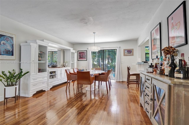 dining room with bar, beverage cooler, and light wood-type flooring