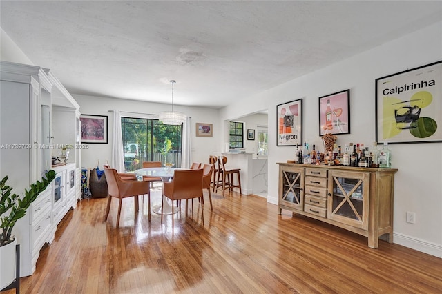 dining space featuring indoor bar and light hardwood / wood-style flooring