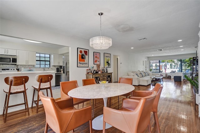 dining room with wood-type flooring, sink, and a notable chandelier