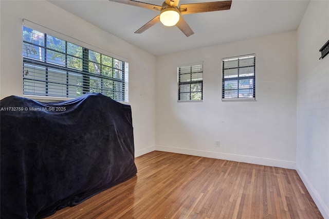 bedroom with multiple windows, wood-type flooring, and ceiling fan