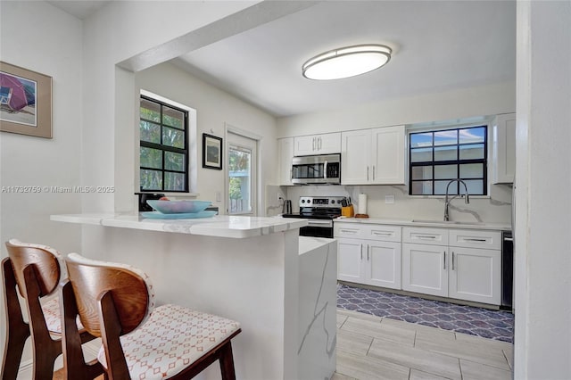 kitchen with white cabinetry, stainless steel appliances, a breakfast bar, and kitchen peninsula