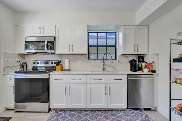 kitchen with tasteful backsplash, white cabinetry, sink, light tile patterned floors, and stainless steel appliances