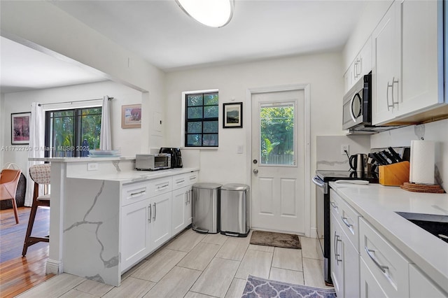 kitchen featuring stainless steel appliances, white cabinetry, and kitchen peninsula