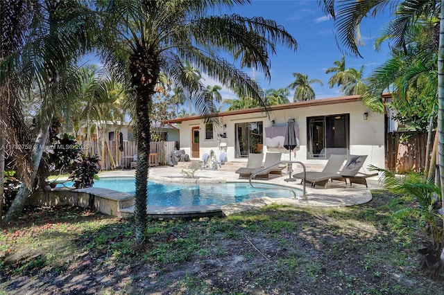 rear view of property with a fenced in pool and a patio area