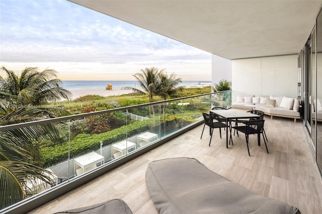 balcony featuring a water view, an outdoor living space, and a view of the beach