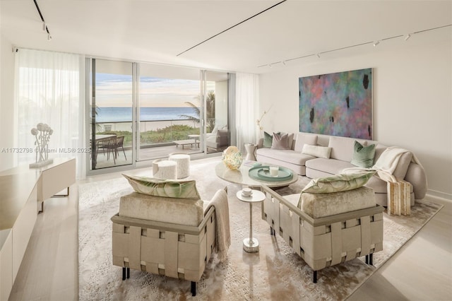 living room featuring expansive windows, a water view, and track lighting