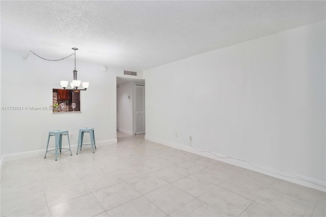 unfurnished room featuring a textured ceiling and an inviting chandelier