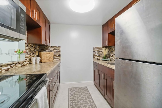 kitchen with light stone counters, stainless steel appliances, tasteful backsplash, and light tile patterned floors