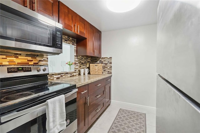 kitchen with tasteful backsplash, light stone countertops, and appliances with stainless steel finishes