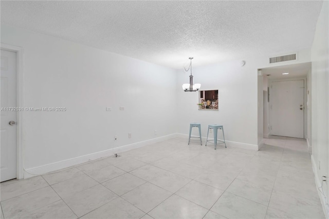 unfurnished room featuring a notable chandelier and a textured ceiling