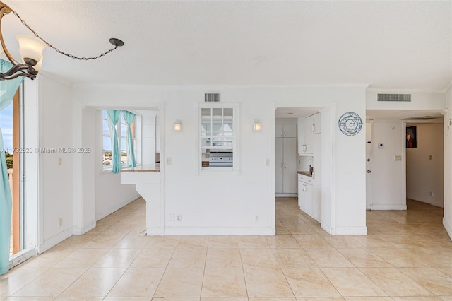 tiled spare room with ornamental molding and a textured ceiling