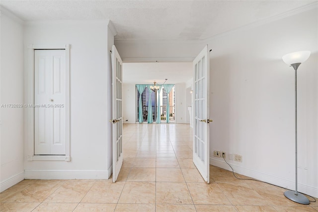 hallway with ornamental molding, a notable chandelier, a textured ceiling, and french doors