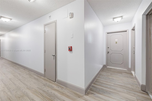 hallway featuring light hardwood / wood-style floors and a textured ceiling