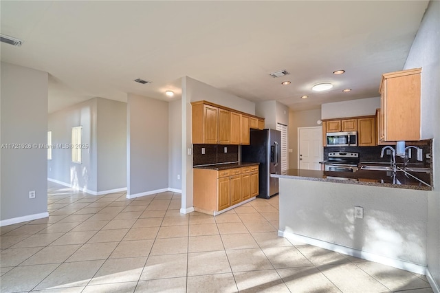 kitchen featuring light tile patterned flooring, sink, appliances with stainless steel finishes, kitchen peninsula, and decorative backsplash