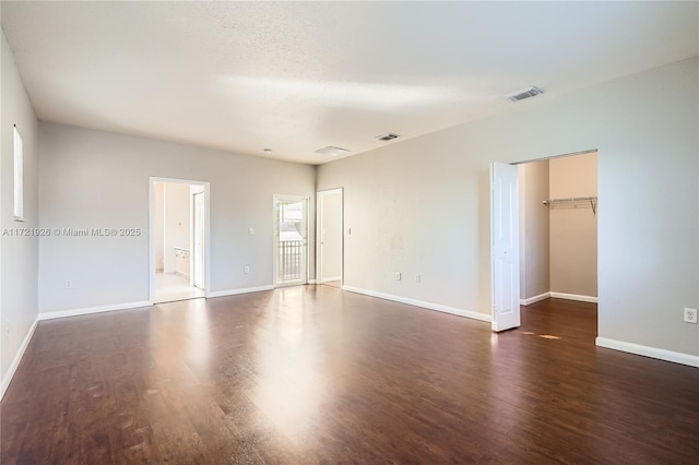 unfurnished bedroom with dark hardwood / wood-style floors and a spacious closet