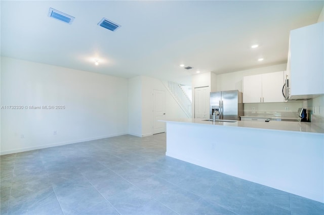 kitchen featuring sink, light tile patterned floors, appliances with stainless steel finishes, white cabinets, and kitchen peninsula