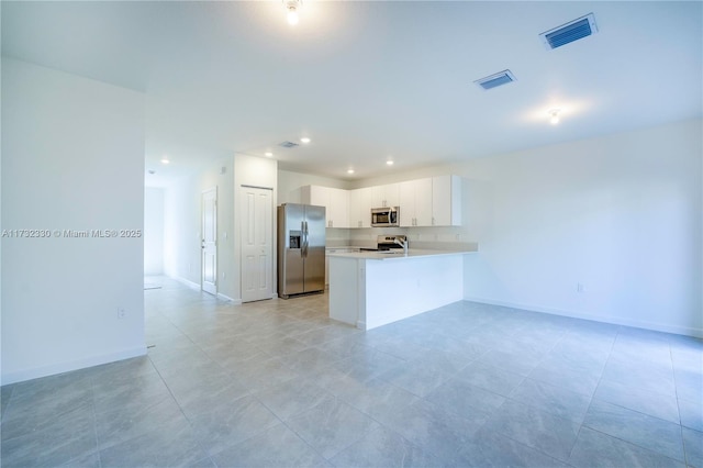 kitchen with stainless steel appliances, kitchen peninsula, and white cabinets