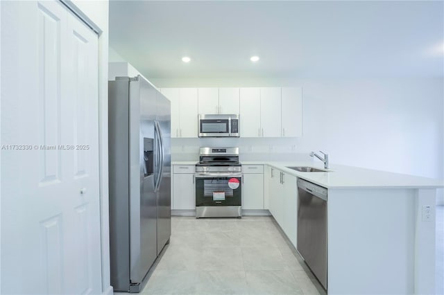 kitchen with white cabinetry, stainless steel appliances, kitchen peninsula, and sink