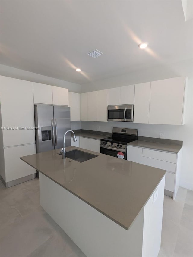 kitchen with stainless steel appliances, an island with sink, sink, and white cabinets