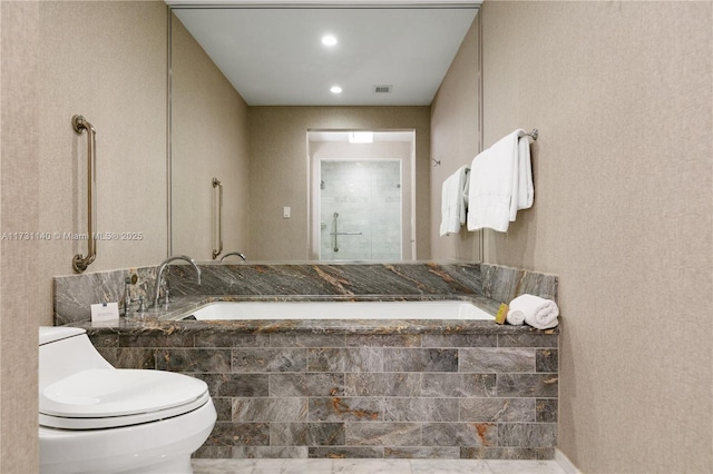 bathroom featuring tiled tub and toilet