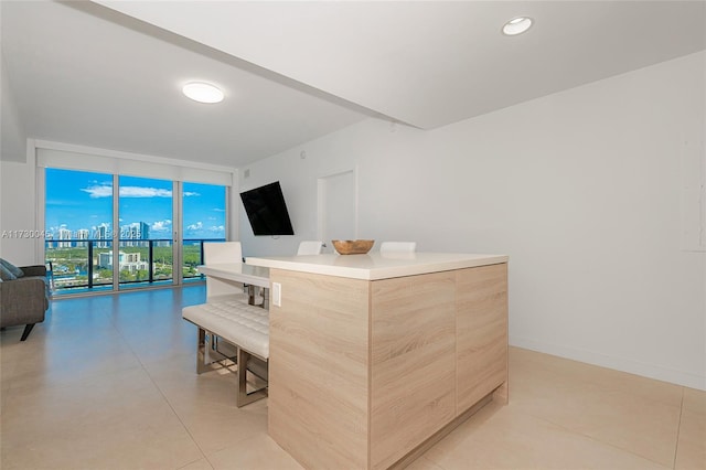 kitchen with baseboards, modern cabinets, a kitchen island, open floor plan, and light brown cabinets