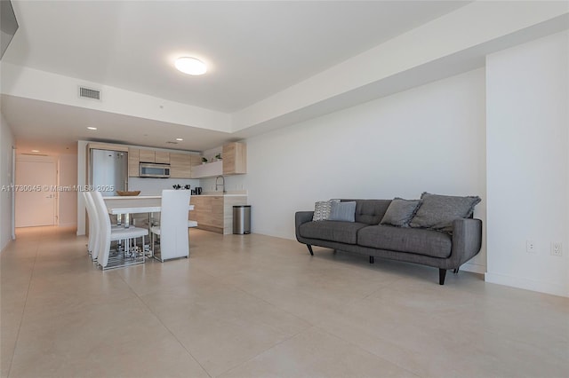 living area featuring concrete flooring, baseboards, visible vents, and recessed lighting